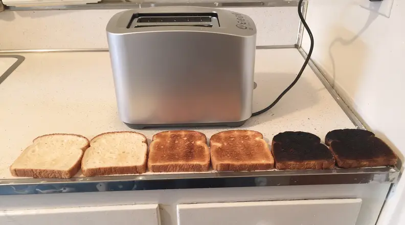Six pieces of toast of varying doneness laid out in front of the best toaster pick, the Breville