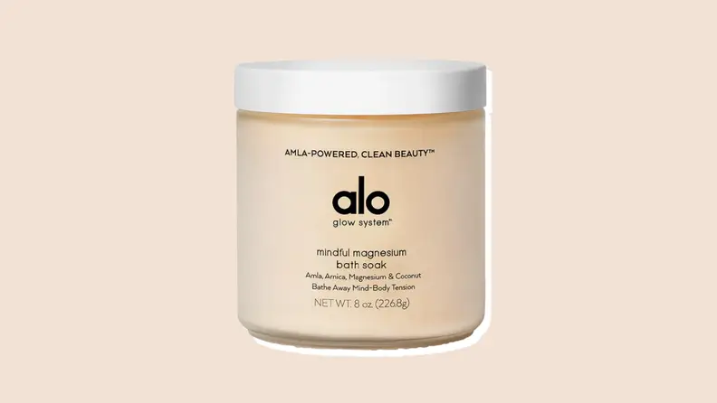 A tan container of Alo Yoga's Glow System Mindful Magnesium bath soak on a neutral background.