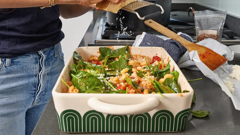 Cheese is grated onto a pasta dish inside the Great Jones Hot Dish.