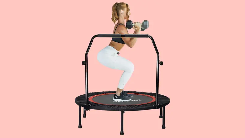 A woman squatting on a Freedare mini trampoline with weights in her hands.