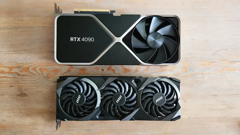 Two graphics cards lying flat on a wooden table side by side.