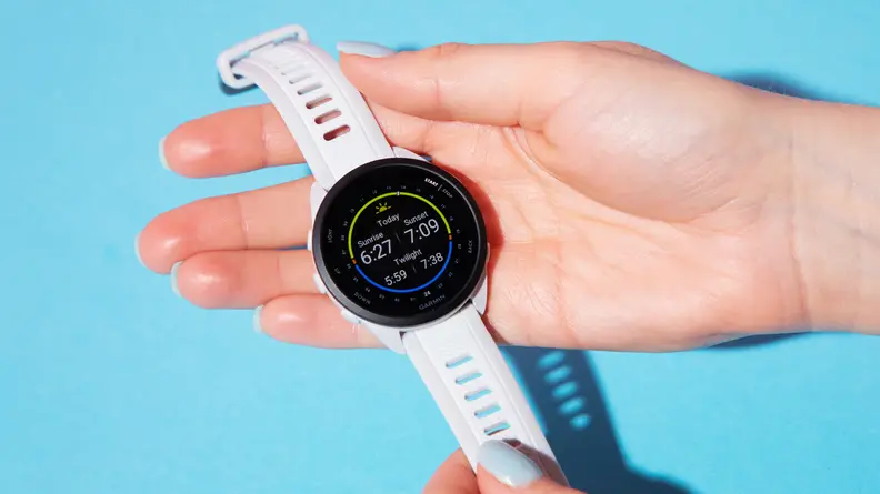 A person holding the Garmin Forerunner 165 watch on a blue background.