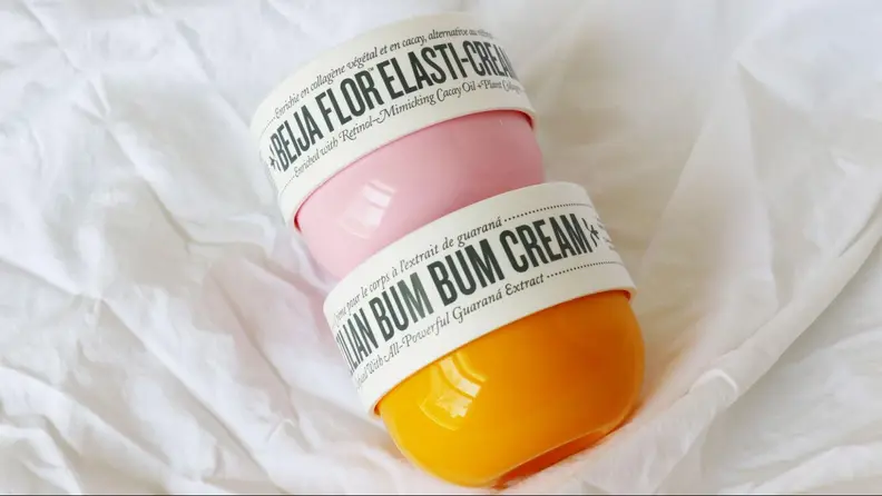 Two tubs of body lotion sit on a sheet.