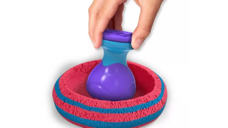 A hand plays with kinetic sand.