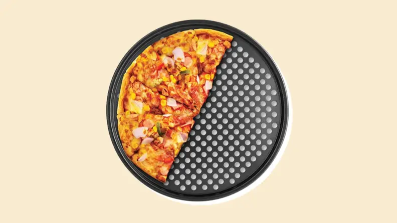Half a pizza on a perforated tray on a beige background.