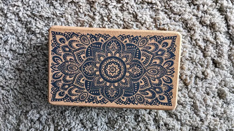 Yoga Design Lab Block resting on a carpeted floor