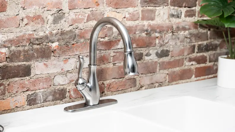 A silver faucet is attached to a white kitchen sink