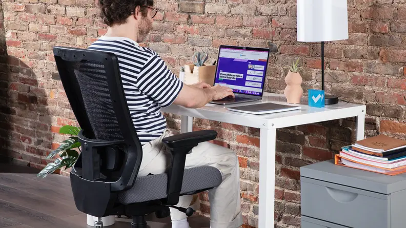Person sitting in the Tempur-Pedic office chair while working on laptop computer.