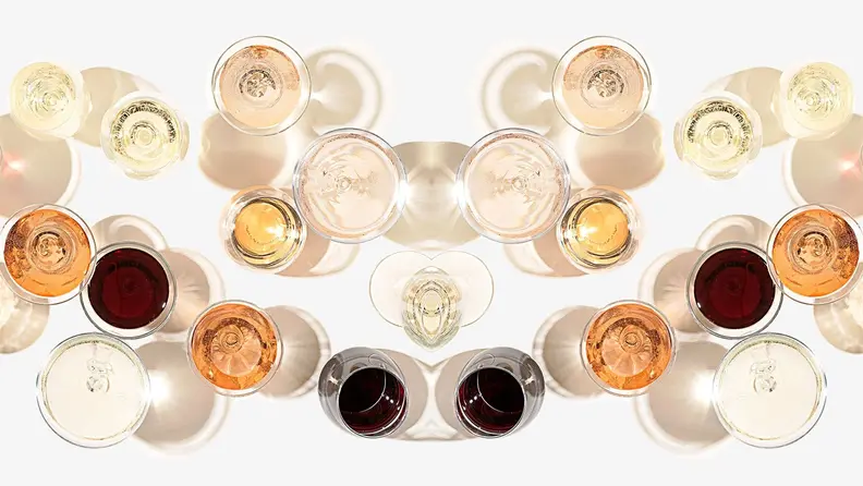 Shot from above, a spread of glasses of red, white, orange, and rosé wines on a white background.