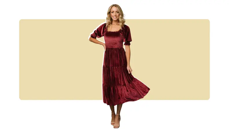 A model wearing a red velvet midi dress that has puffed short sleeves.