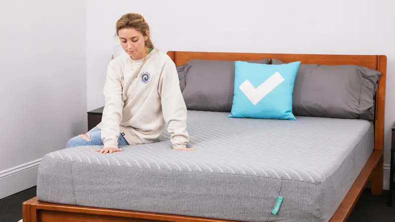 A person sitting on the Siena Memory Foam mattress.