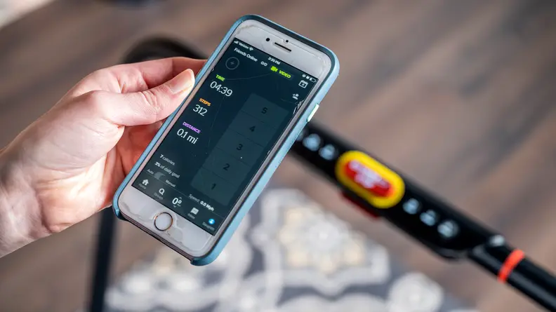 A hand holding a phone showing the Treadly app on the screen.