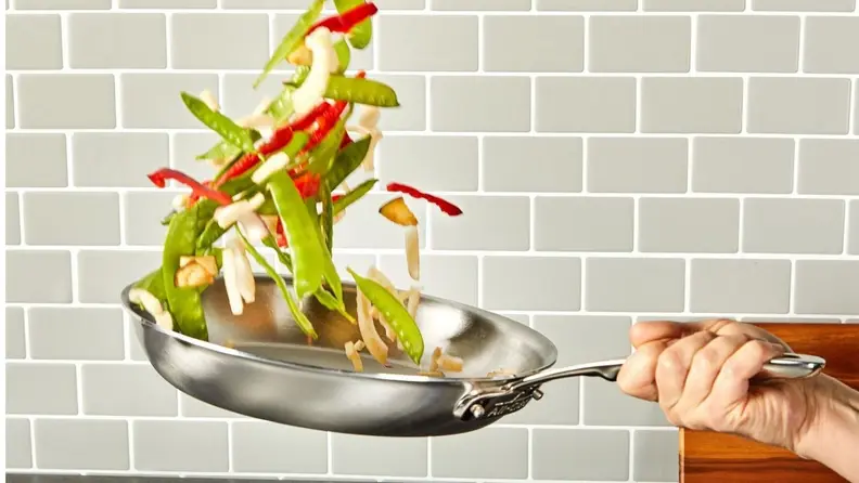 A chef tosses vegetables in a skillet.