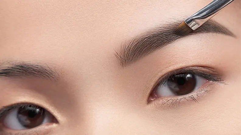 A woman fills in her brows with the Anastasia Beverly Hills Brow Powder Duo.
