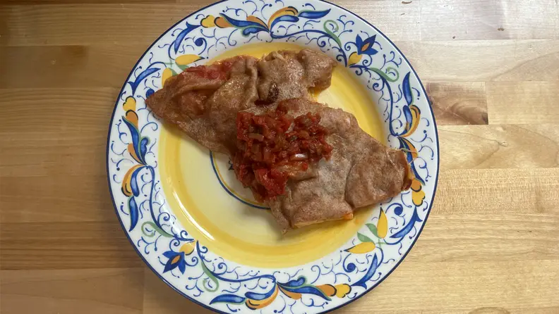 Cooked meat sitting on top of plate on wooden countertop.