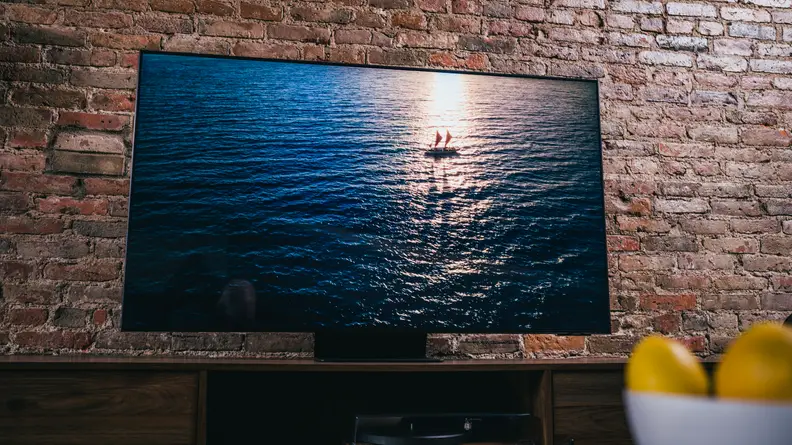 The TV shows a boat in shadow floating upon a dark blue sea that's lit by sunrise