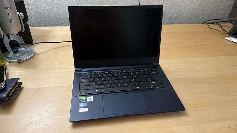 Origin EON14-S gaming laptop sitting on top of wooden surface with black screen display.