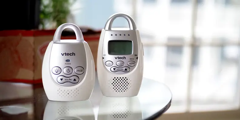 A VTech Safe & Sound DM221 baby audio monitor, base and receiver, on a glass tabletop.