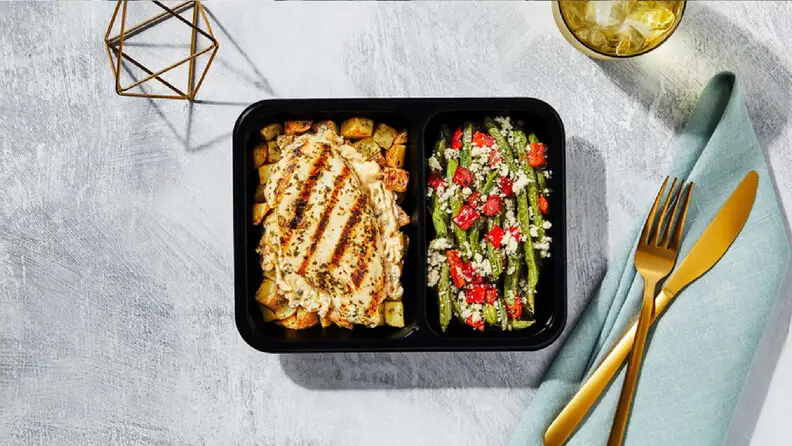 Seared chicken on a bed of potatoes next to asparagus with crumbly cheese