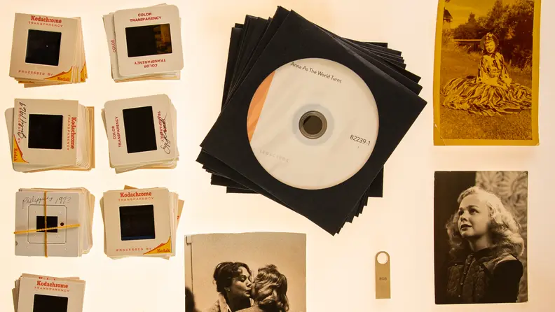 A stack of DVDs, photos slides, and old black and white photos.
