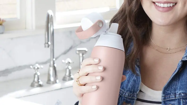 A person clutches a pink water bottle.