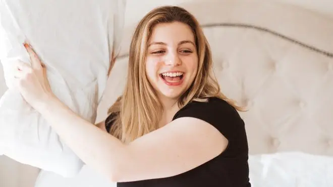 A person holds a pillow in a silk pillowcase