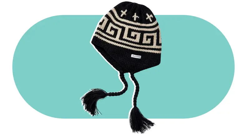 A black ear-flap beanie with beige patterns on it.