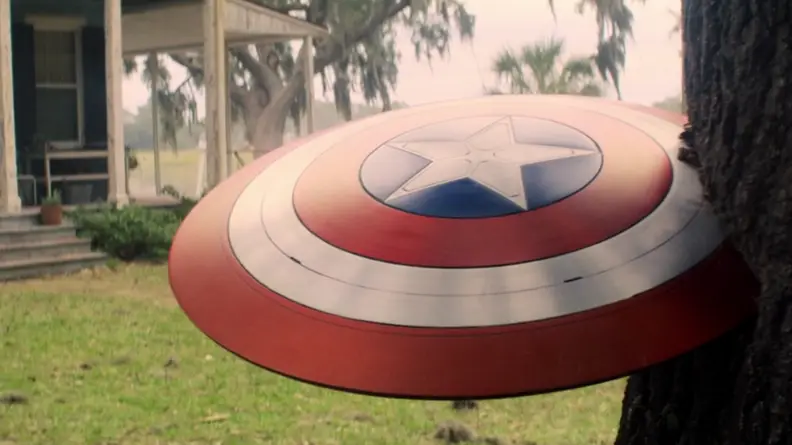 A screenshot from The Falcon and the Winter Soldier featuring Captain America's shield jutting out of a tree trunk.