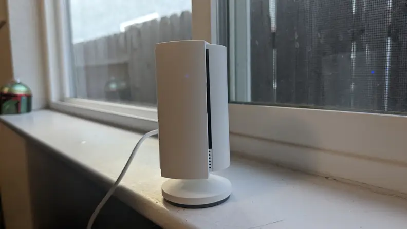 The second-gen Ring Indoor Cam with solid, white privacy screen covering camera while sitting on window sill in front of closed window.