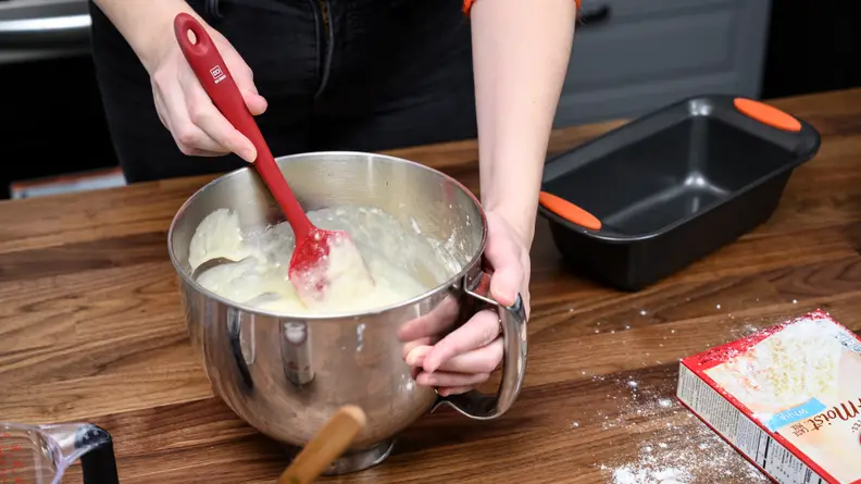A person mixing batter with a silicone spatula