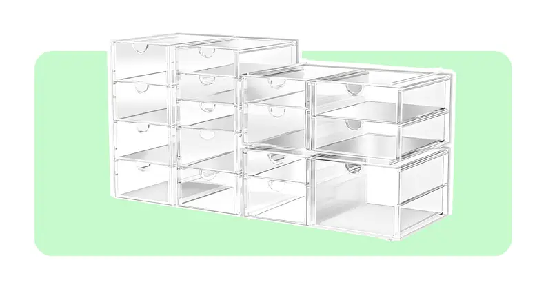 Multiple stacked empty clear storage bins in front of light green background.
