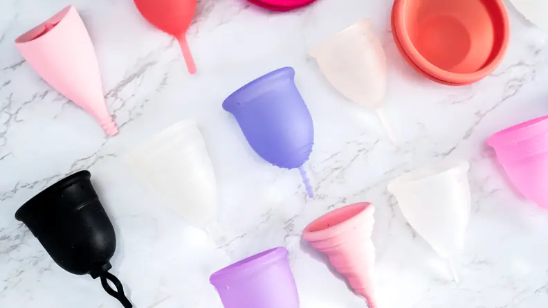 colorful menstrual cups on white marble background.