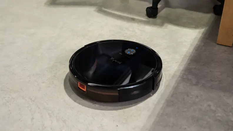 The Kyvol Cybovac on a concrete floor attempting to navigate furniture