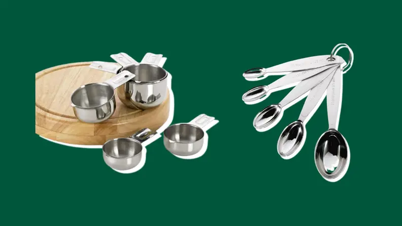 Stainless steel measuring cups and spoons on a green background