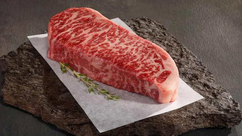In the center of the image, tehre's a piece of uncooked American Wagyu beef by Snake River Farms.