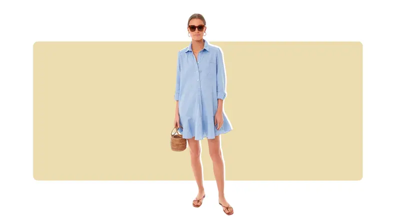 A chambray shirt dress that has a ruffled hem, a half-button, and long sleeves.