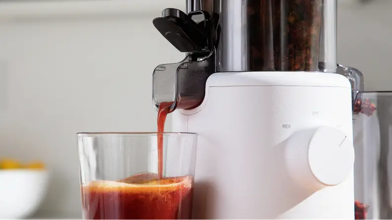 The juicer slowly pouring juice into a glass.