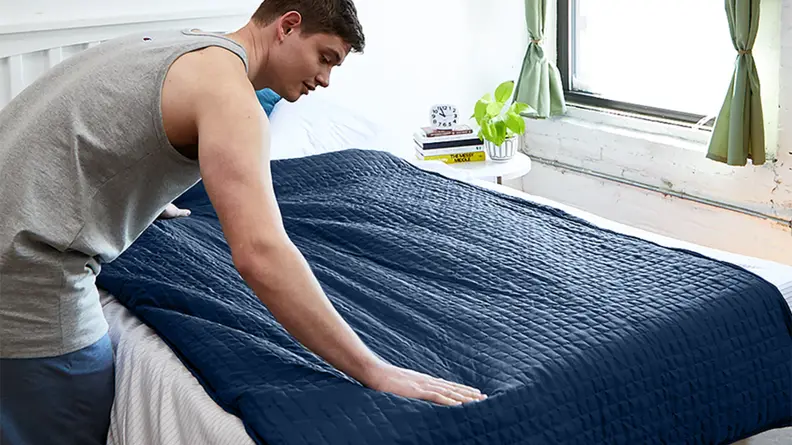 Man lying a Gravity Blanket on a bed