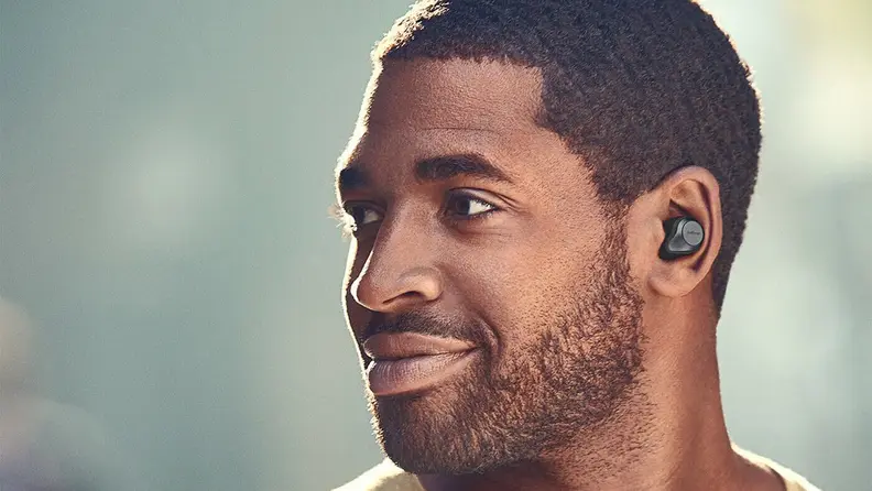 A person wears earbuds outside.