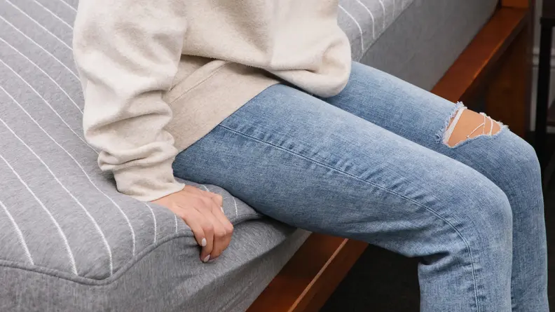 A person sitting on the edge of the Siena Memory Foam mattress.