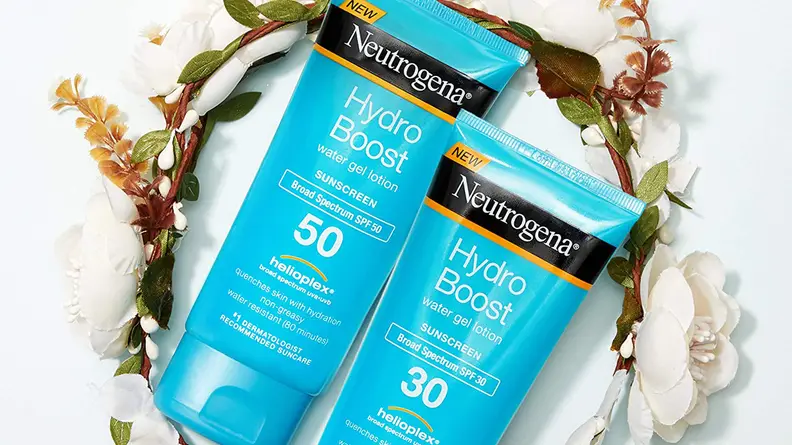 Two turquoise bottles of sunscreen lay on top of a circular flower vine.