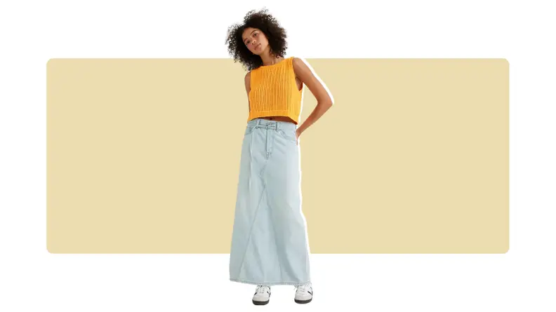A model wearing an oversized light blue denim maxi skirt with a yellow top.
