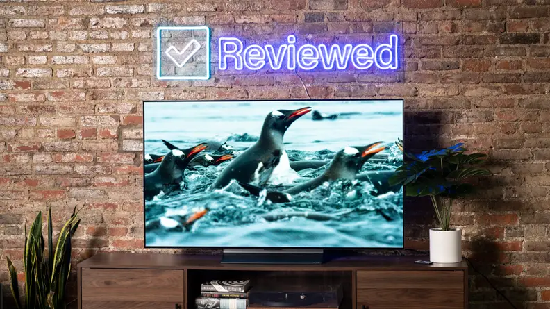 LG television on a table under a neon Reviewed logo