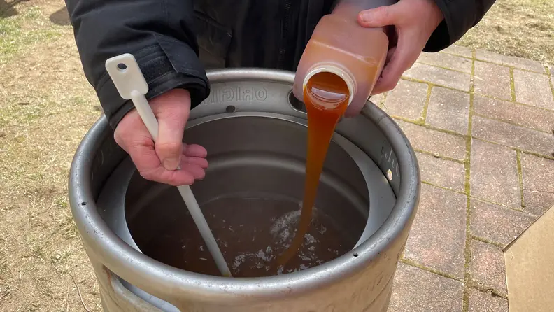 My dad is pouring the malt into the mixture and stirring with a giant spoon.
