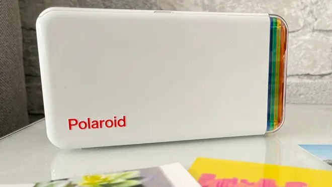 White polaroid printer sitting on counter top.