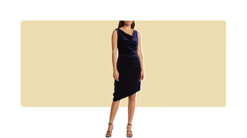 A model wearing a navy blue velvet dress that has an asymmetrical hem.