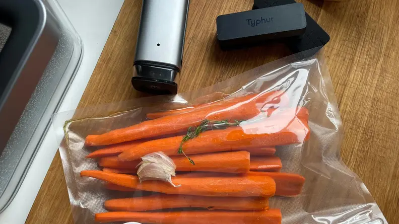 Carrots inside of vacuum sealed bag next to the Typhur vacuum sealer.