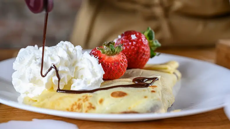 A sweet crepe with strawberry, Nutella, and whipped cream.