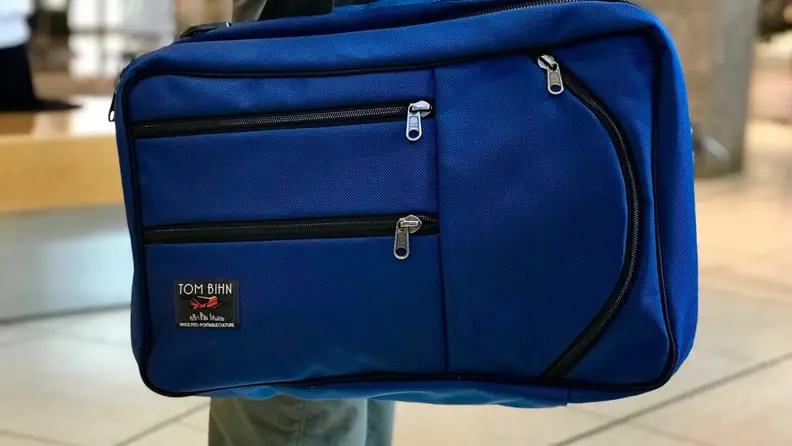 A woman holds a Tom Bihn Western Flyer by its handle