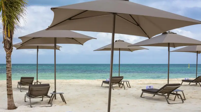A photograph of a beach in Mexico with four beach umbrellas open